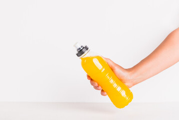 Isotonic water energy drink copy space white background. Woman hand take bottle with yellow...