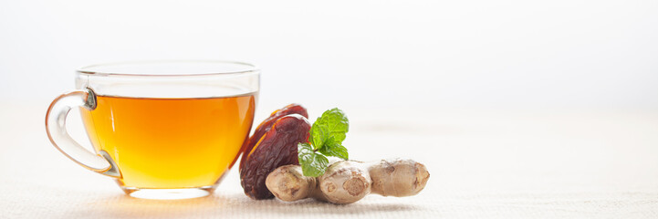Hot warming tea with dates and ginger in a glass cup on the table. Immune drink