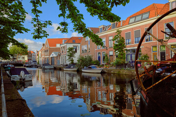 HAARLEM, NETHERLANDS - MAY 24, 2022: Clear reflections of canal-side houses on the Burgwal canal on a sunny evening.