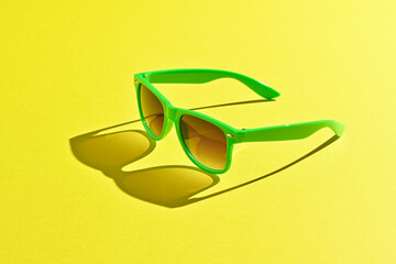 Gafas de sol de color verde sobre fondo amarillo