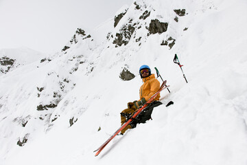 Man skier with skitour equipment is rest on the snowy hill