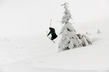 athlete skier masterfully jumping over slopes of snow-capped mountains. Ski touring, freeride extreme sport