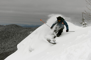 Active man rides down with splashing powdered snow on mountain on splitboard