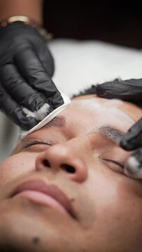 Vertical close-up of cleaning of excess ink after male microblading procedure