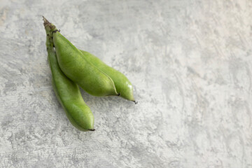 Bouquet of fresh broad beans in shell on a vintage background and space for text