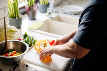 Obraz na płótnie Canvas Male hands cooking salad in cozy kitchen