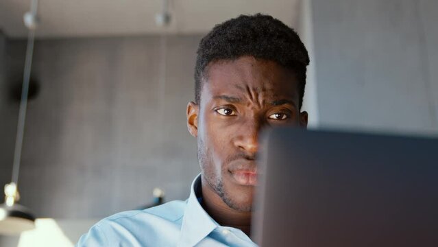 Young emotional african american man professional working using computer