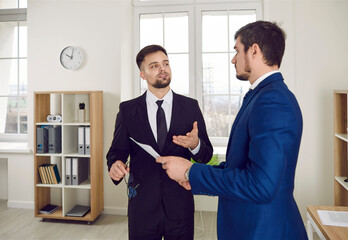 Young real estate agent, mortgage broker, or business advisor in suit meeting new client in his...