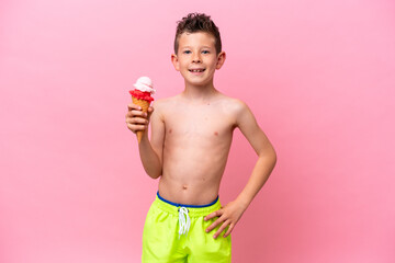 Little caucasian boy eating an ice-cream isolated on pink background smiling a lot