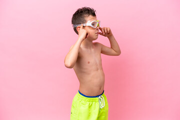 Little caucasian boy wearing a diving goggles isolated on pink background having doubts and thinking © luismolinero