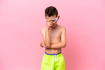 Little caucasian boy wearing a diving goggles isolated on pink background laughing