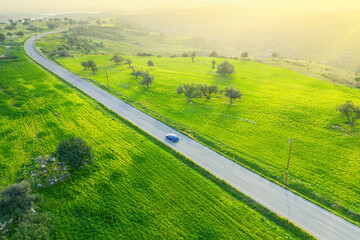 Groen landschap op het platteland met een auto die over een asfaltweg rijdt en een auto, drone-weergave van bovenaf