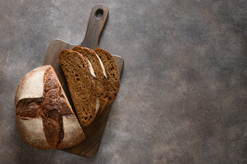 Loaf of freshly baked Hemp bread on cutting board on gray background. View from above. Copy space.