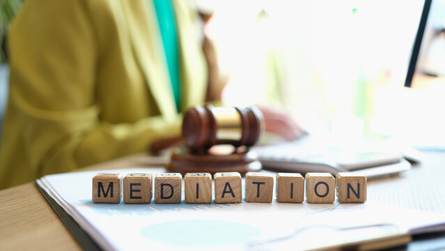 Mediator sitting near gavel of judge and words mediation closeup
