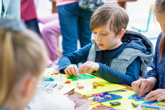 children in the master class make crafts from colored paper and plasticine