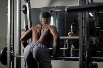 Fototapeta na wymiar Handsome afro american man posing showing back muscles in gym. 