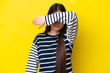 Young Chinese woman isolated on yellow background covering eyes by hands