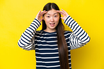 Young Chinese woman isolated on yellow background with surprise expression