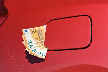 A bundle of fifty euro banknotes in the fuel tank cap of a car