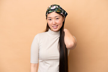 Young Chinese woman isolated on beige background laughing
