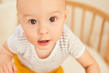 Portrait of a cute little boy standing in a crib.