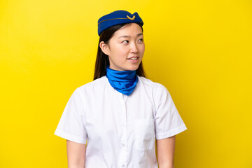 Airplane Chinese woman stewardess isolated on yellow background looking side