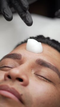 Close-up applying cleansing foam to remove microblading ink
