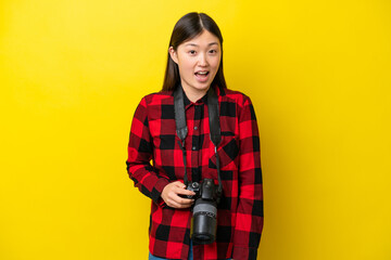 Fototapeta premium Young photographer Chinese woman isolated on yellow background with surprise facial expression