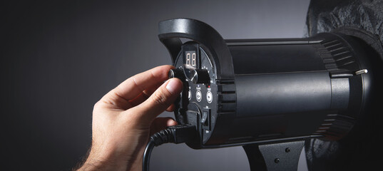 Male hand adjusts flash in studio.