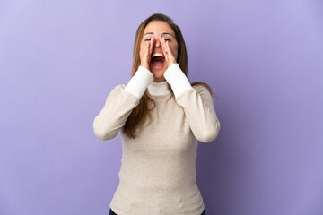 Middle age Brazilian woman isolated on purple background shouting and announcing something