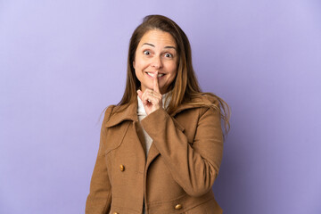 Middle age Brazilian woman isolated on purple background showing a sign of silence gesture putting finger in mouth