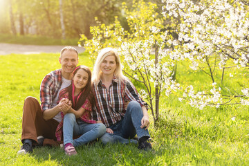 Fototapeta premium Happy family spending good time together in spring in a flowering garden
