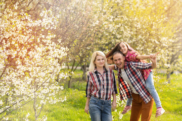 Fototapeta premium Happy family spending good time together in spring in a flowering garden