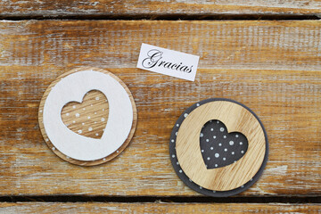 Gracias (thank you in Spanish) card with two wooden hearts on rustic surface

