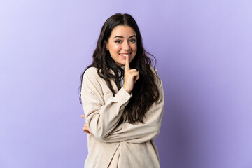 Fototapeta premium Young caucasian woman isolated on purple background showing a sign of silence gesture putting finger in mouth