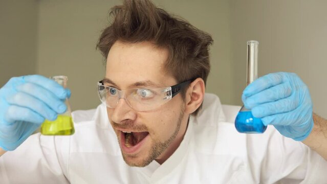 Crazy mad chemist scientist holding test tube with his successful experiment in laboratory.