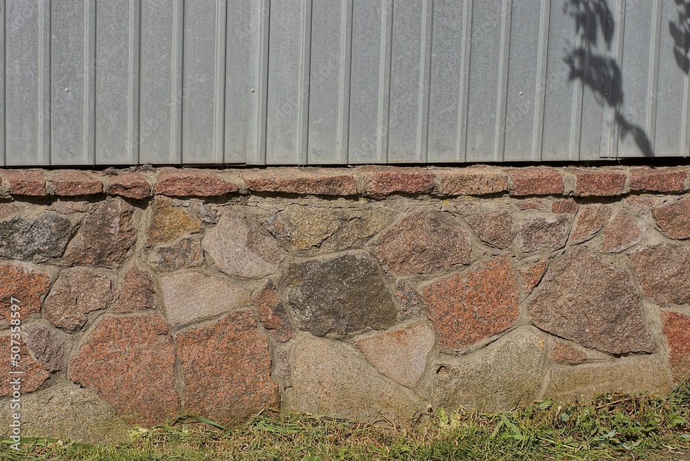 Poster texture of brown stone foundation and gray metal in the wall of the fence on the street