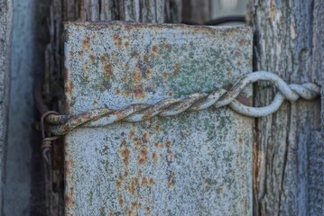 old rusty iron wire on a gray concrete pole and wood wall