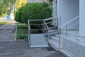 gray stone steps and a threshold with white metal handrails outside on asphalt