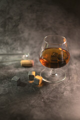 transparent whiskey with a bottle and a wooden cork on a dark background. whiskey stones in a glass