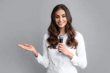 Young pretty woman singing a song with a microphone, presenting an event or having a party. Happy...