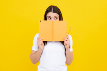 Female student holds books isolated on yellow background in studio. English language school, education concept.