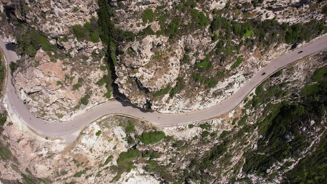 une route sinueuse au milieu des rocher avec des voitures et des moto