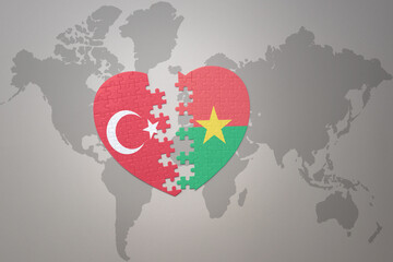puzzle heart with the national flag of turkey and burkina faso on a world map background. Concept.