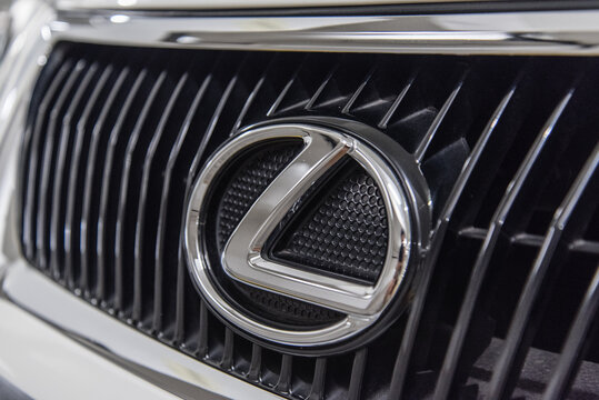 Close-up of Lexus logo badge and car grill on a white Lexus IS luxury sports sedan.