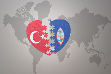 puzzle heart with the national flag of turkey and guam on a world map background. Concept.