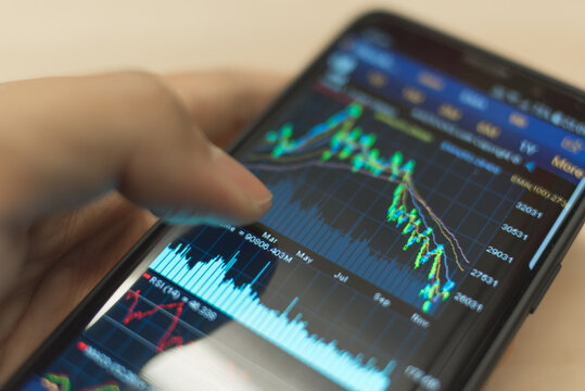 Graph showing Hang Seng Index (HSI) of Hong Kong Stock Market falling displayed on a smartphone screen held my a man.