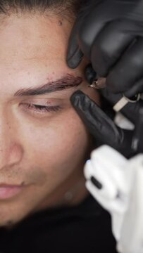 Close up shot of half male face microblading procedure to making permanent eyebrows makeup