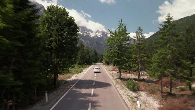 Drone flying behind car on mountain road in Valbone valley, Albania. Concept of road trip summer vacation