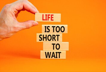 Life is short to wait symbol. Concept words Life is too short to wait on wooden blocks on a beautiful orange table orange background. Businessman hand. Business motivational life or wait concept.